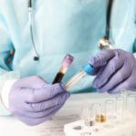 Doctor wearing gloves holds a blood test tube
