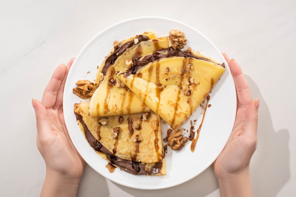 Tasty Crepes With Chocolate Spread And Walnuts on Plate